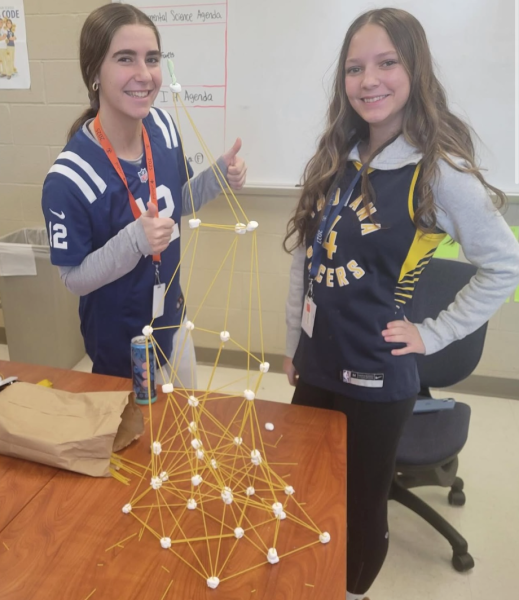 Two students, senior Abby Beasley and sophomore Abigail Eldridge, stand in front of their spaghetti and marshmallow tower. These two cadets demonstrated teamwork and engineering skills through a fun hands-on activity. Sophomore Abigail Eldridge said, “Through CAP I’ve learned the basics of aviation, I’m working towards my pilot's license, and I’ve had many amazing experiences.”